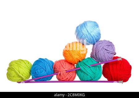 Row of yarn balls stacked on one end to form a triangle with purple knitting needles skewered through. Isolated on white background. Stock Photo