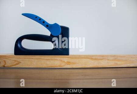A construction stapler on a wooden bar. Beautiful white background. Copy space. Stock Photo