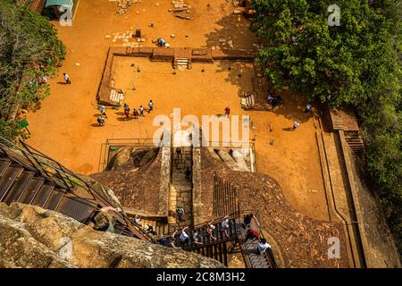Tourists climbing the Lion's Gate stairs to the top of the Sigiriya Rock Fortress in Sri Lanka on a sunny day Stock Photo