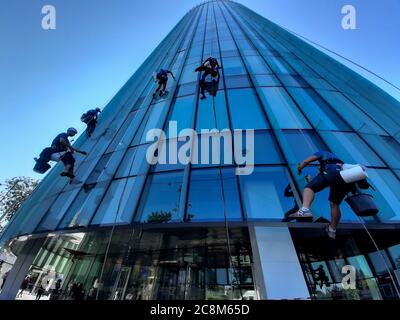 Bucharest, Romania - July 22, 2020: Five industrial climbers wash the windows of a high office building in Bucharest. Stock Photo