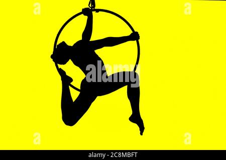 silhouette of man in tall acrobatic hoop with elegant pose and yellow illuminated background Stock Photo