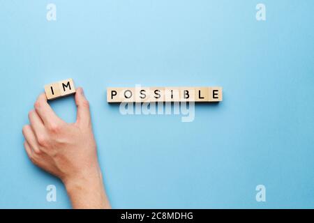 The concept of the possible from the impossible. Hand on a blue background with wooden blocks Stock Photo
