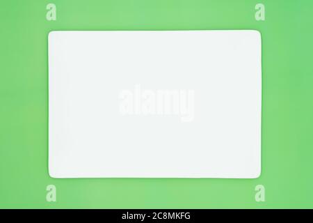 A rectangle empty white plate isolated on the light green background. Stock Photo