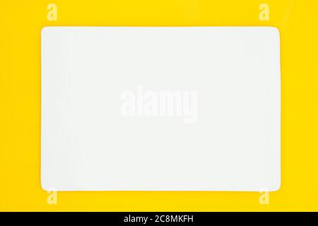 A rectangle empty white plate isolated on the yellow background. Stock Photo