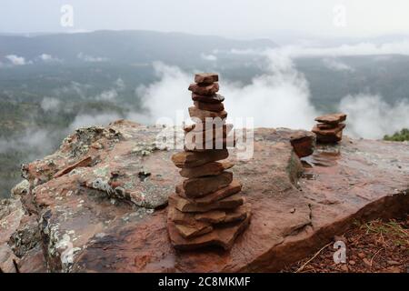 Cairns stacked tall along the trail on the Mogollon Rim, in Northern Arizona with the clouds below, after a summer storm. Stock Photo