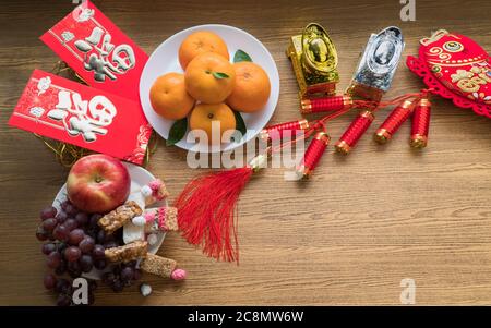 Flat lay Chinese new year festival decorations with orange apple grape and red packet. Texts appear in image meaning good fortune Stock Photo