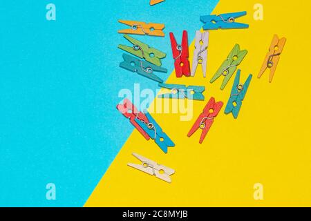 Colorful decorative wooden clothespins on yellow and blue background. Stock Photo