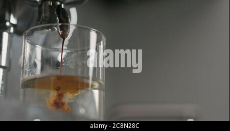 low angle pour from coffee machine into glass with water Stock Photo