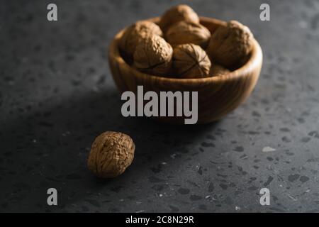 inshell walnuts in olive wood bowl on terrazzo countertop Stock Photo