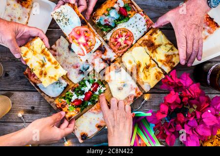 Close up view of table full of caucasian group people hands taking italian pizza and eat together in friendship for celebration party - concept of hap Stock Photo