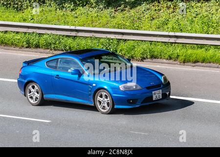 2006 blue Hyundai Coupe SE; 2dr fastback Vehicular traffic moving vehicles, cars driving vehicle on UK roads, motors, motoring on the M6 motorway highway network. Stock Photo