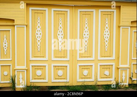 Wooden wide gates in old Russian houses. Figurative ornaments made of wood.Bright colors. Ancient wooden Russian houses. Stock Photo