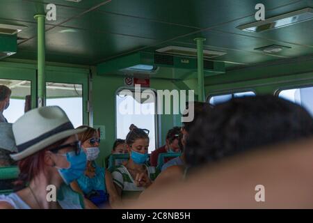 Venice, Italy - July 5th, 2020: People on board of a vaporetto wearing protective masks. Stock Photo