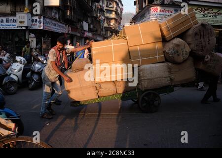 Two men steer a heavy handcart through Kalbadevi Rd. in Bhuleshwar, Mumbai, India, handcarts being the most used mode for goods transport in the area Stock Photo