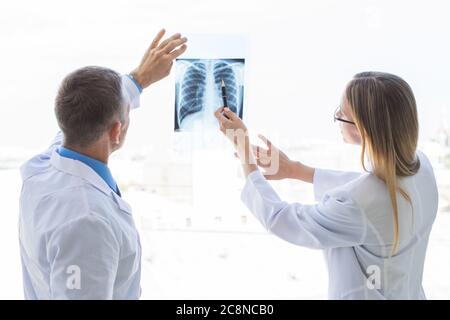 Two doctors examining a x-ray film by the window at clinical office Stock Photo