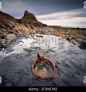 An old rusty iron mooring ring in front of Holy Island castle. Stock Photo