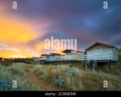 Beach huts on stilts amonst the grassy dunes at Old Hunstanton. Stock Photo