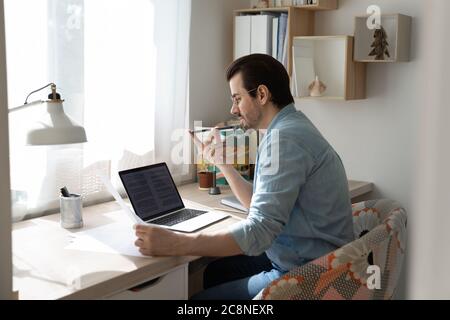 Back view of man record audio message working on laptop Stock Photo