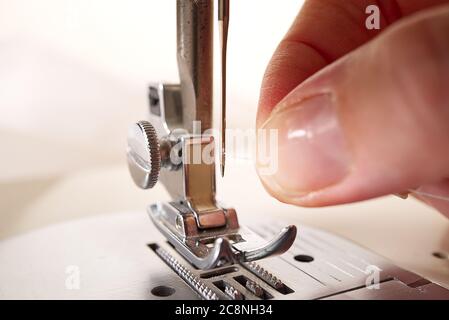 woman threading a needle on a sewing machine. close up, selective focus. Stock Photo