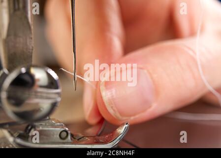 woman threading a needle on a sewing machine. close up, selective focus. Stock Photo