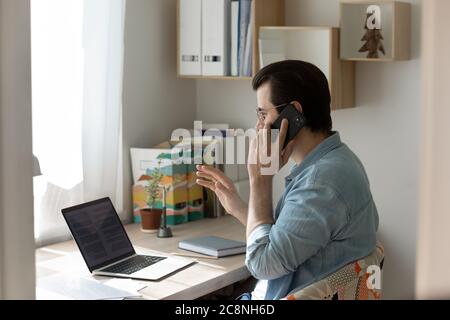 Young man work on laptop talking on cellphone Stock Photo