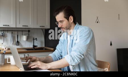Focused young male freelancer work on laptop from home Stock Photo