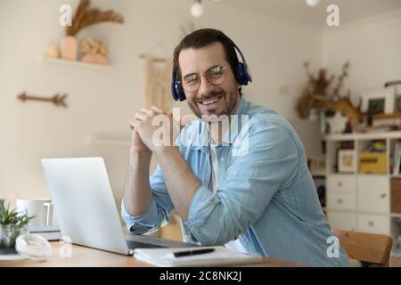 Portrait of smiling young man in headphones at home workplace Stock Photo