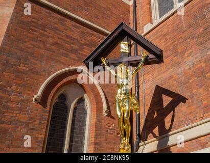 St Mary Magdalene Church, Paddington, London, completed in 1870s in densely packed slum. WW1 memorial of Christ (cast iron & gilded) on wooden cross. Stock Photo