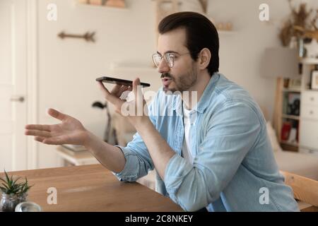 Young man talk on cellphone using voice assistant Stock Photo