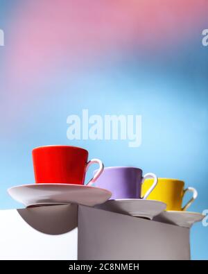 Violet, Yellow and red cup for coffee stand on a white cube Stock Photo