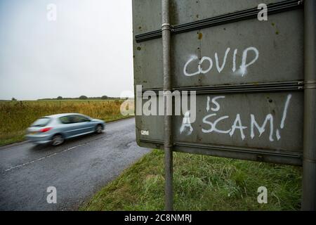 Graffiti sprayed on a road sign in Dorset expressing the opinion that coronavirus is a scam. Dorset England UK GB Stock Photo