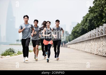 group of five young asian adult men and woman running training outdoors Stock Photo