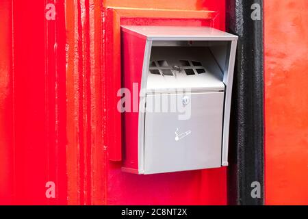 Cigarette smokers steel metal ashtray fitted to red wall Stock Photo