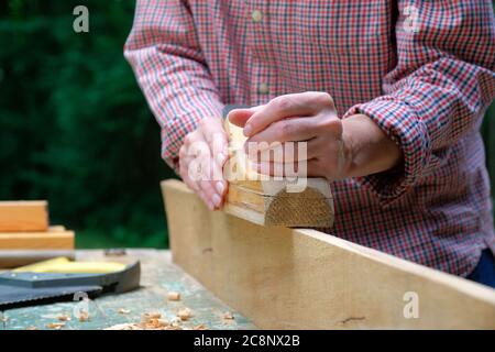 Caucasian craftswoman working in her workshop using carpentry plane. Woodworking concept. Stock Photo