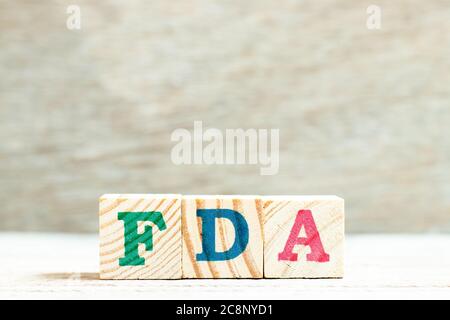 Alphabet letter in word FDA (abbreviation of food and drug administration) on wood background Stock Photo