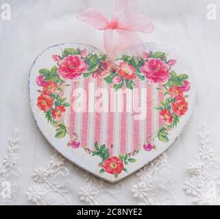 Valentine's card background - wooden heart decorated in decoupage technique Provencal style on a textile white background with place for text. A nice Stock Photo