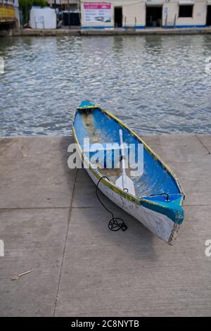 Rowboat with paddle docked in Belize City Belize near The Swing Bridge with random fork on ground Stock Photo