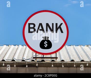A Circle billboard with sign a Bank and money bag, is installed on a roof. Board with sign of finance service and bank. Stock Photo