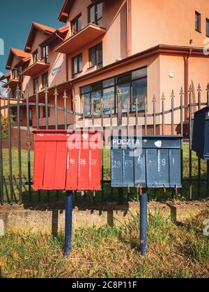 red and blue mailboxes standing on a street in a village in Poland Stock Photo