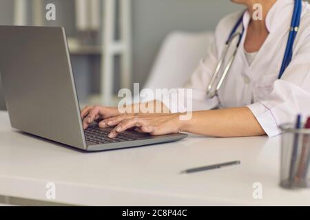Concept doctor online. Doctor's hands are typing on a laptop keyboard a message web chat consultation medical clinic. Stock Photo