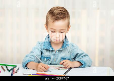 Cute boy doing homework writing and painting. Children paint Stock Photo