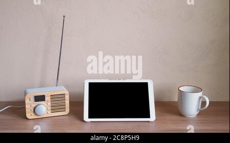 tablet computer with retro radio and coffee cup on desk - blank screen and wall with copy space Stock Photo