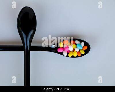 Multi colored sweet fennel sugar candy in black spoons against white background with copy space, isolated Stock Photo