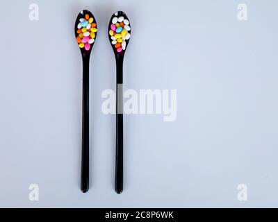 Multi colored sweet fennel sugar candy in black spoons against white background with copy space, isolated Stock Photo