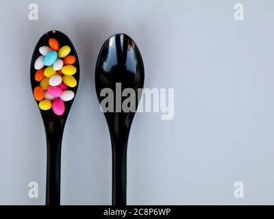 Multi colored sweet fennel sugar candy in black spoons against white background with copy space, isolated Stock Photo