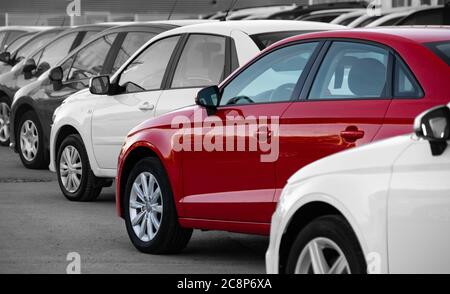 Black and white image of a row of cars. Only the red car has color Stock Photo
