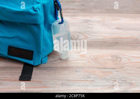 School, coronavirus days. Hand sanitizer gel and school bag backpack on wooden desk background, close up view, Template, copy space Stock Photo
