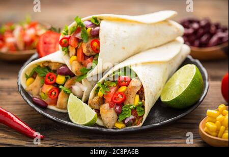 Fresh tortilla wraps with chicken meat and vegetables on the wooden table Stock Photo