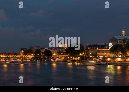View over the river seine to the bridge Pont des Arts and Pont Neuf and the towers from Notre Dame in the background by night.