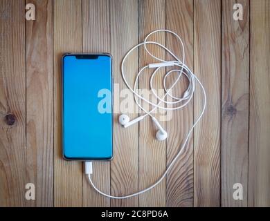 Smartphone and headphones on a wooden background. Stock Photo